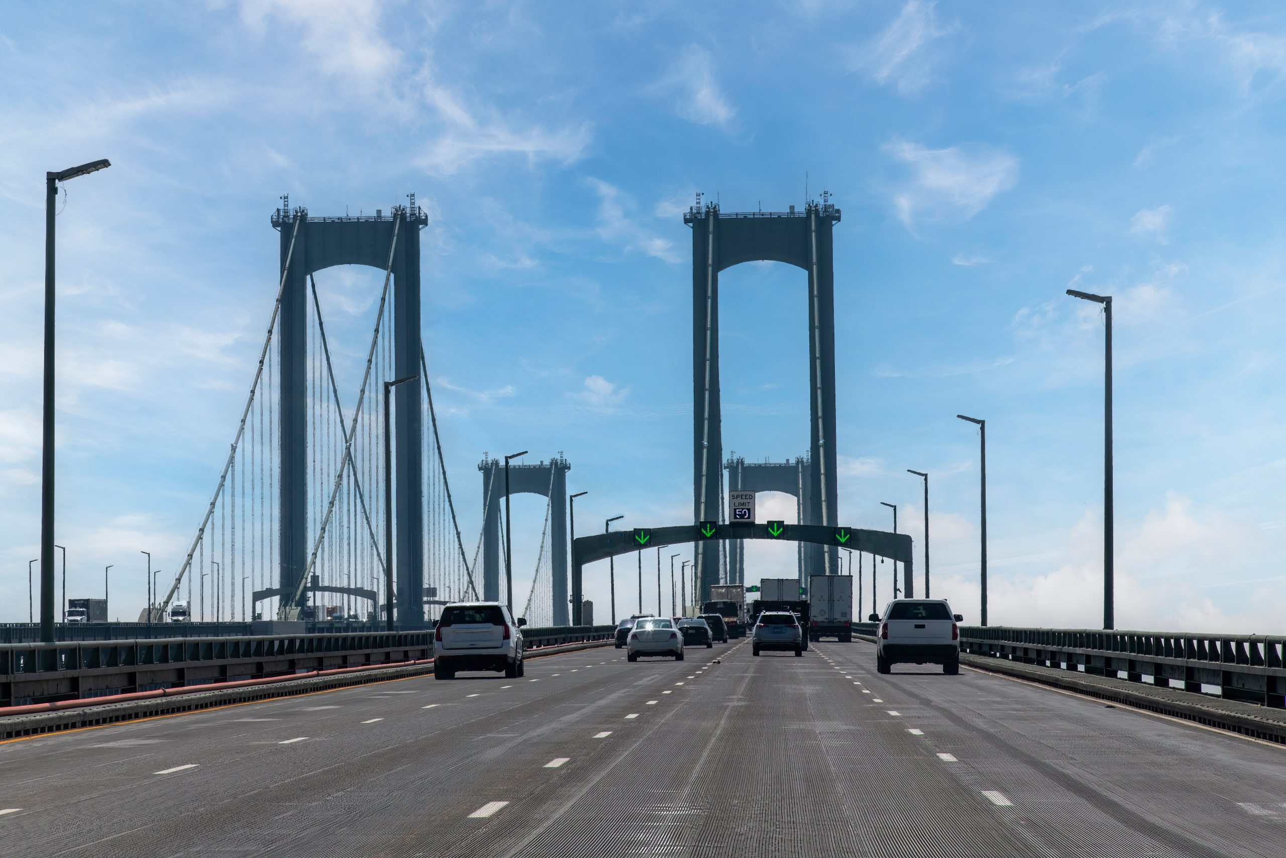 Drivers perspective on Delaware Memorial Bridge near Wilmington, DE, USA in northerly direction with cars on road crossing the Delaware River against a blue sky Drivers perspective on Delaware Memorial Bridge near Wilmington, DE, USA in northerly direction with cars on road crossing the Delaware River against a blue sky