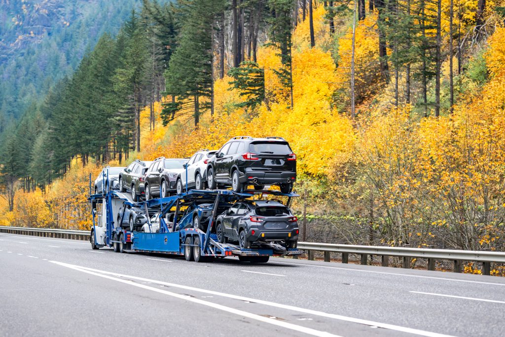 car shipping during fall season, semi truck with cars loaded on large freeway