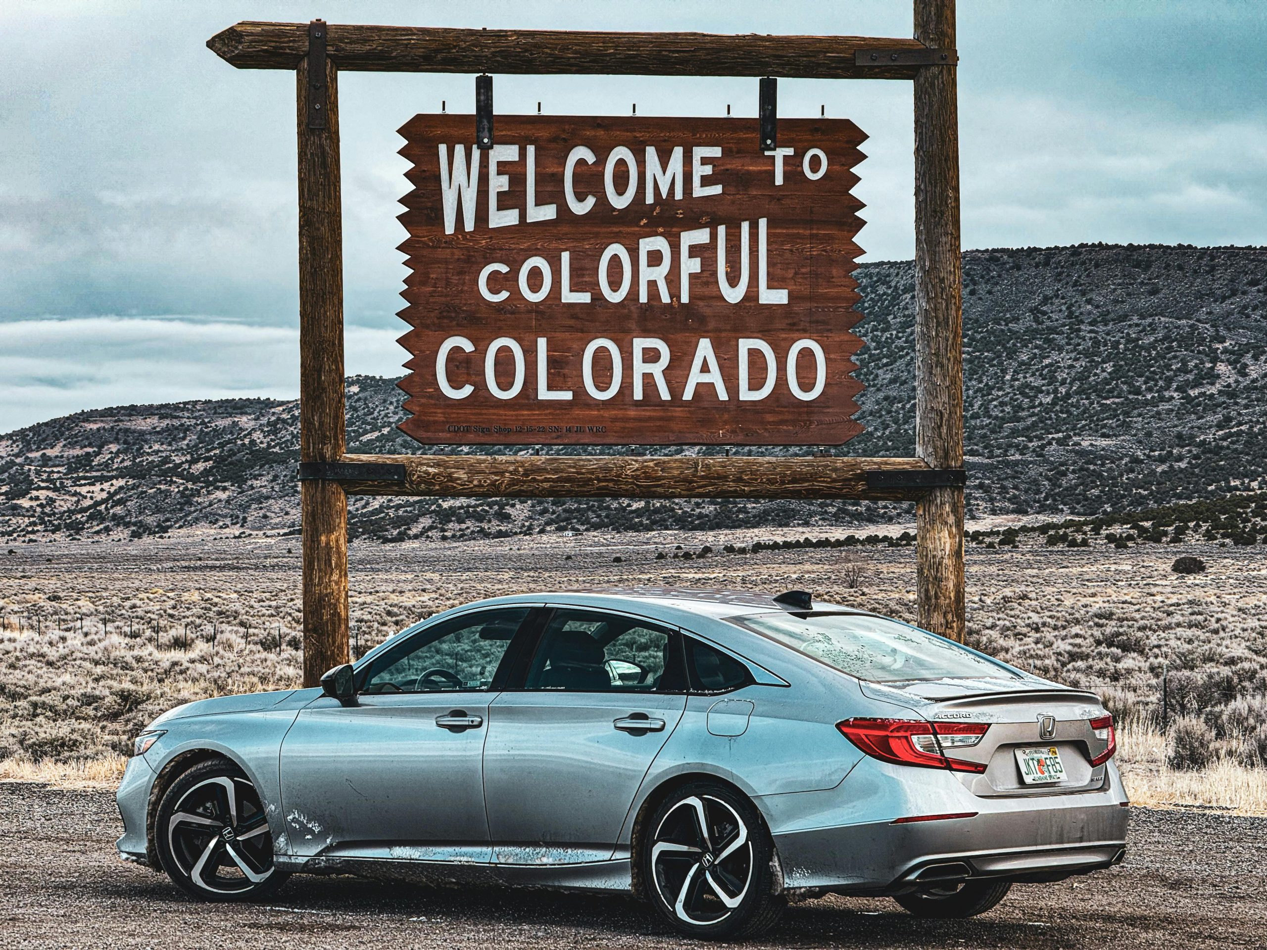 pexels-steve-burcham-626383500-28933802 welcome to colorado sign with a white car underneath it