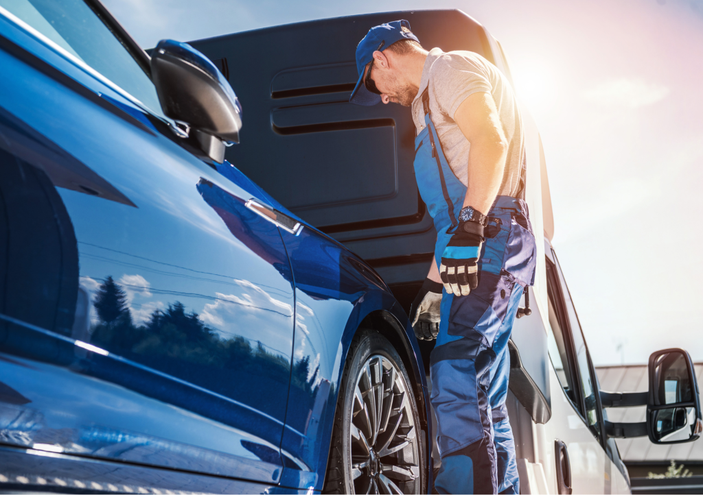 Man loading car onto truck bed for auto shipping.