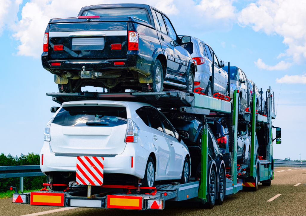 Open carrier auto transport with multiple cars on truck bed. 